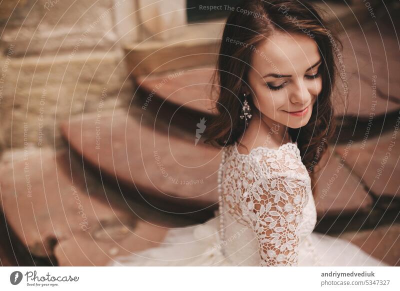 Porträt einer schönen jungen Braut in einem weißen Hochzeitskleid mit langen Haaren in der alten europäischen Stadt. Frau in der Nähe von alten Gebäude. Hochzeitstag