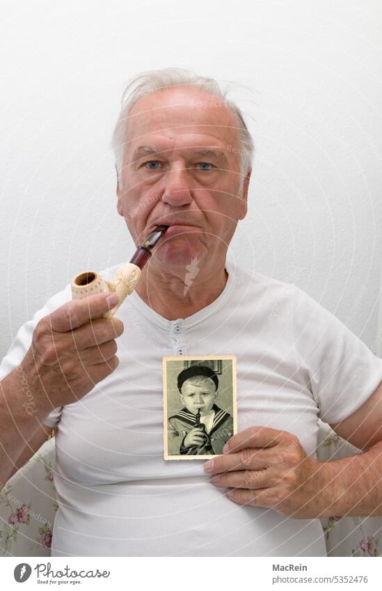 Mann mit Pfeife und ein Bild aus Kindertagen 60-70 jahre alt mann erwachsener rentner kind kinderfoto halten festhalten pfeife porträt retro sitzt unterhemd