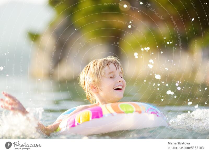 Kleiner Junge schwimmen mit bunten schwimmenden Ring im Meer auf sonnigen Sommertag. Nettes Kind spielt in sauberem Wasser. Familie und Kinder Resort Urlaub während der Sommerferien.