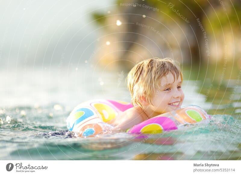 Kleiner Junge schwimmen mit bunten schwimmenden Ring im Meer auf sonnigen Sommertag. Nettes Kind spielt in sauberem Wasser. Familie und Kinder Resort Urlaub während der Sommerferien.