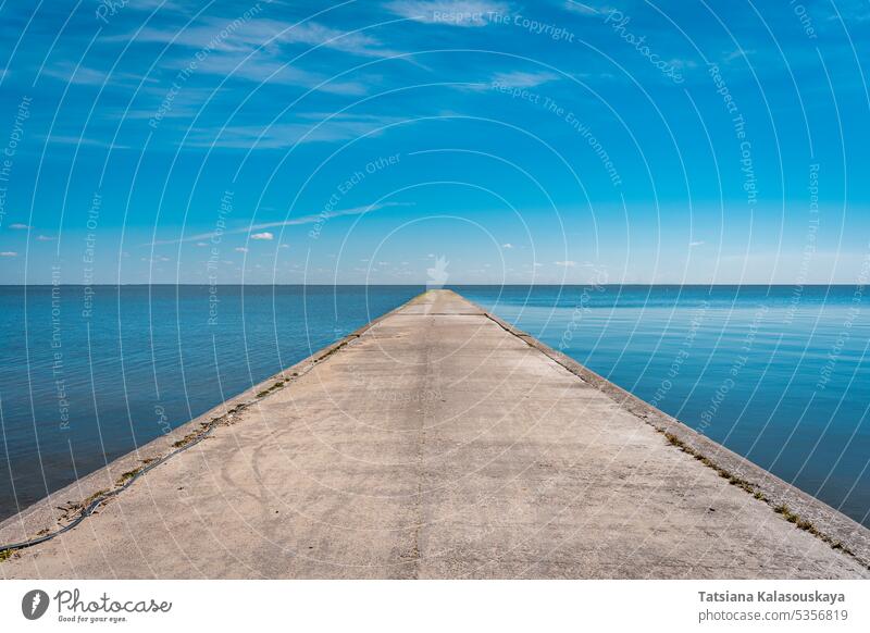 Eine lange steinerne Seebrücke reicht weit ins Meer hinein, vor dem Hintergrund eines blauen, klaren Himmels. Stein MEER Pier Wasser Tag Horizont Felsen