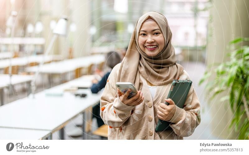 Porträt einer asiatischen muslimischen Studentin, die in einer Bibliothek steht echte Menschen Teenager Campus positiv Prüfung Wissen selbstbewusst schulisch