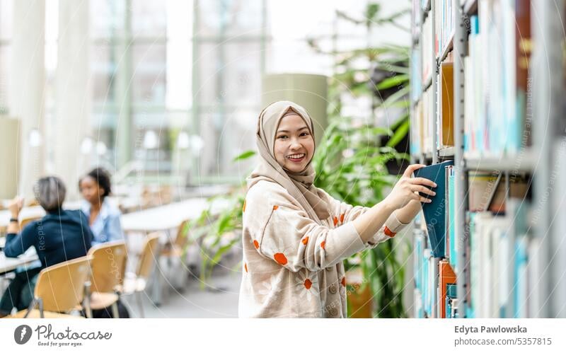 Porträt einer asiatischen muslimischen Studentin, die in einer Bibliothek steht echte Menschen Teenager Campus positiv Prüfung Wissen selbstbewusst schulisch