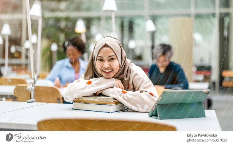 Multiethnische Gruppe von Studenten, die in einer Bibliothek sitzen und gemeinsam lernen echte Menschen Teenager Campus positiv Prüfung Wissen selbstbewusst