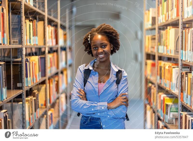 Porträt einer schwarzen Studentin, die in einer Bibliothek steht echte Menschen Teenager Campus positiv Prüfung Wissen selbstbewusst schulisch Erwachsener