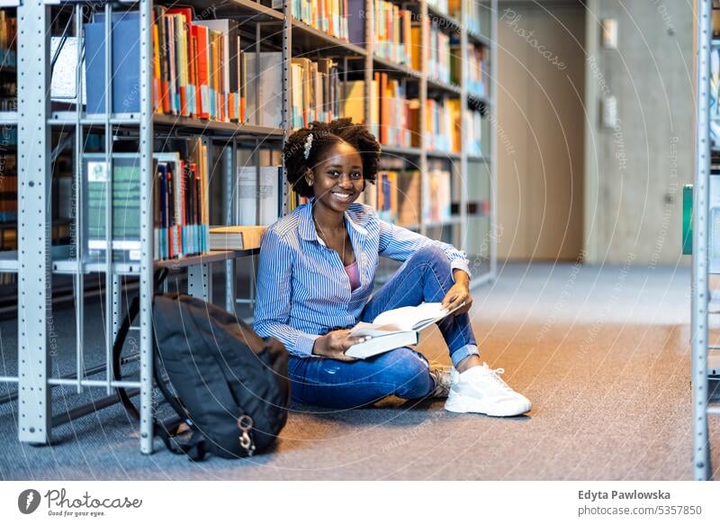 Schwarze Studentin liest ein Buch in einer Bibliothek echte Menschen Teenager Campus positiv Prüfung Wissen selbstbewusst schulisch Erwachsener Lifestyle