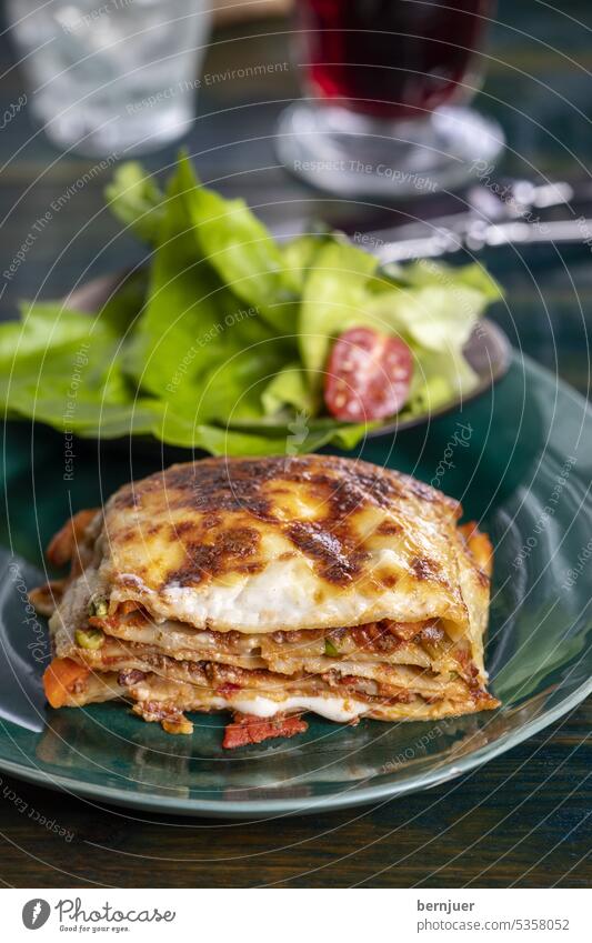 Italienische Lasagne auf grünem Teller rustikal Holz Schicht Erbse Pasta Bolognese gebacken Mahlzeit Essen Abendessen Küche gekocht Käse geschmolzen Gemüse heiß