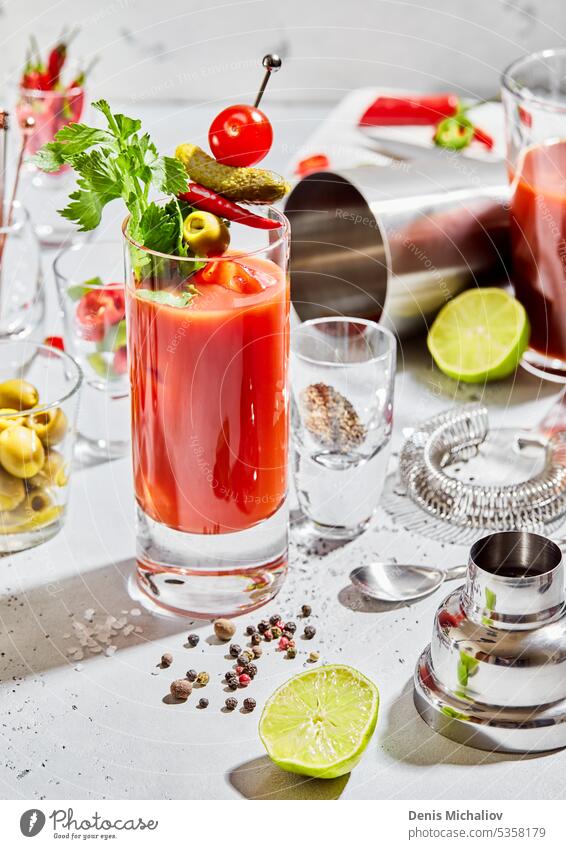 Zubereitung eines Bloody-Mary-Cocktails in einer Bar mit Utensilien und Limette, Pfeffer, Oliven auf einem Leuchttisch. blutig Schüttler Löffel Vodka Paprika