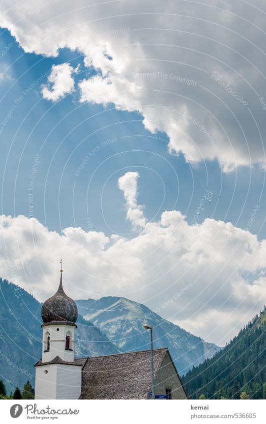 Kirche im Dorf Landschaft Himmel Wolken Sonnenlicht Sommer Schönes Wetter Wald Hügel Felsen Berge u. Gebirge Gebäude Kirchturm blau weiß Idylle Farbfoto