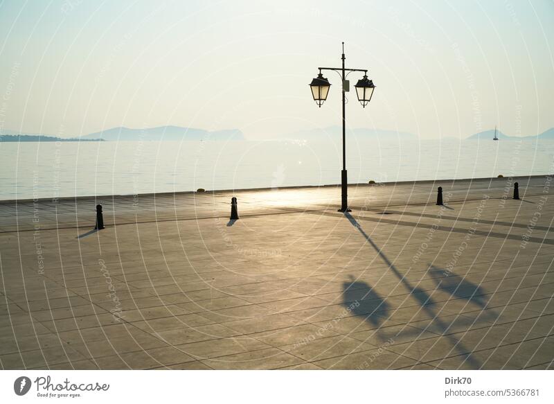 Laterne an der Küste der Ägäis im Morgenlicht Schatten Licht Sonnenlicht Schattenwurf Uferpromenade Straßenlaterne alt historisch Lampe Straßenbeleuchtung