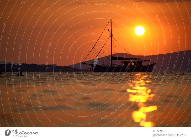 Segelboot im Mittelmeer vor aufgehender Sonne mit Küste im Hintergrund, Aufnahme aus der Froschperspektive Sonnenlicht Sonnenaufgang Licht Außenaufnahme Morgen