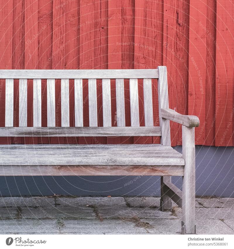 Sonntagsruhe Bank Sitzbank Holzbank Sitzgelegenheit Pause Erholung Einsamkeit ruhig rot blau Fassade verwittert leer Sitzplatz Holzfassade Betonsteine