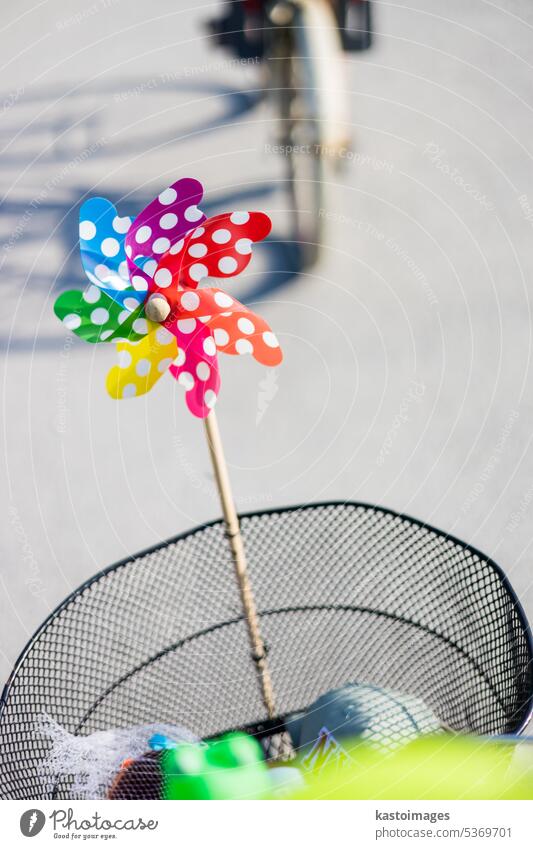 Buntes Windrad, das am Fahrradkorb befestigt ist, um Kleinkinder zu unterhalten, die im Sommer auf dem vorderen Kindersitz auf dem Fahrrad fahren. Windspinner