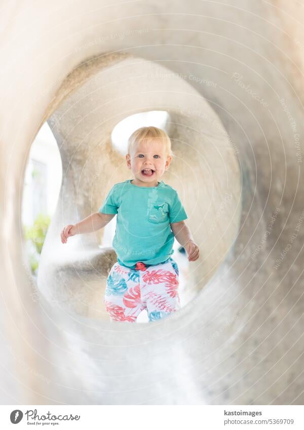 Kind spielt auf Spielplatz im Freien. Kleinkind spielt auf Schule oder Kindergarten Hof. Aktives Kind auf Stein gemeißelter Rutsche. Gesunde Sommeraktivität für Kinder. Kleiner Junge klettert im Freien.