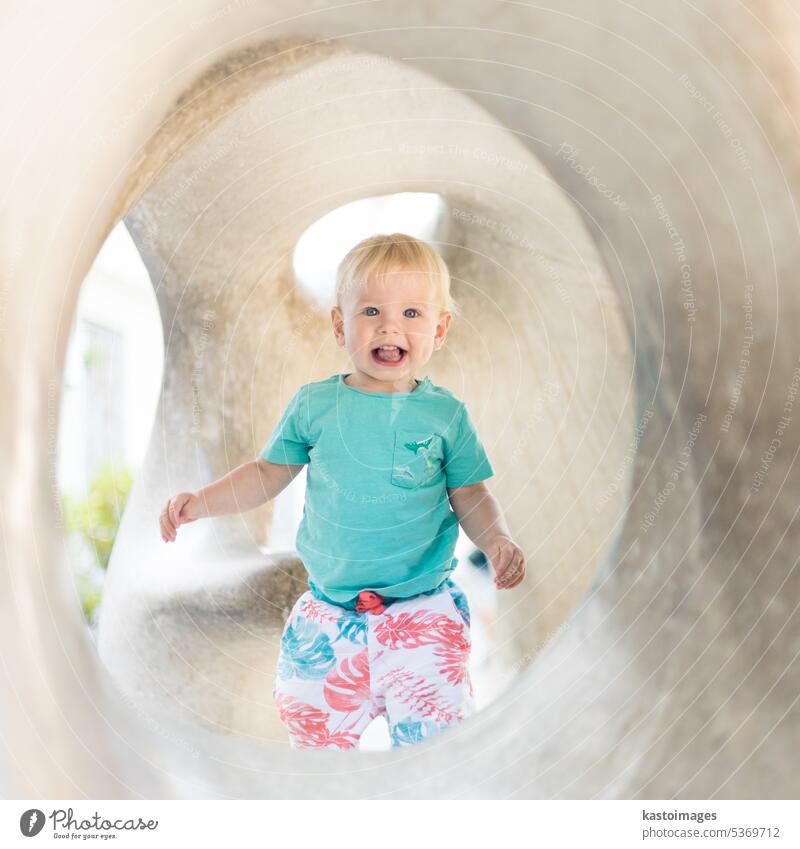 Kind spielt auf Spielplatz im Freien. Kleinkind spielt auf Schule oder Kindergarten Hof. Aktives Kind auf Stein gemeißelter Rutsche. Gesunde Sommeraktivität für Kinder. Kleiner Junge klettert im Freien.