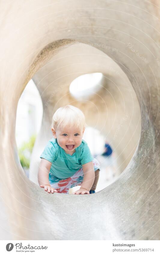 Kind spielt auf Spielplatz im Freien. Kleinkind spielt auf Schule oder Kindergarten Hof. Aktives Kind auf Stein gemeißelter Rutsche. Gesunde Sommeraktivität für Kinder. Kleiner Junge klettert im Freien.