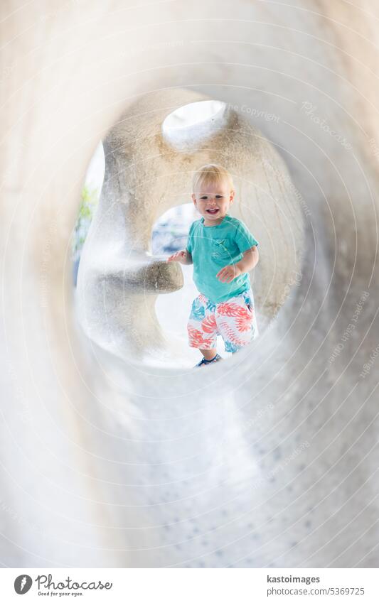 Kind spielt auf Spielplatz im Freien. Kleinkind spielt auf Schule oder Kindergarten Hof. Aktives Kind auf Stein gemeißelter Rutsche. Gesunde Sommeraktivität für Kinder. Kleiner Junge klettert im Freien.