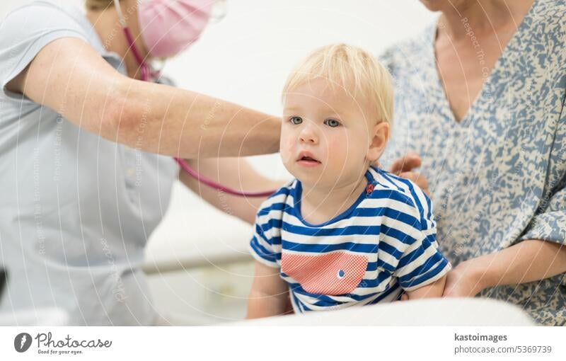 Kleinkind Junge Kind wird von seinem Kinderarzt Arzt während einer Standard-medizinischen Check-up in Anwesenheit und Komfort seiner Mutter untersucht. Nationales Konzept für öffentliche Gesundheit und Kinderbetreuung.