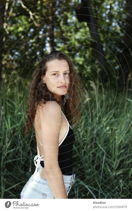 seitliches Portrait einer jungen, schönen, brünetten, Frau vor  einem Wald warm sommerlich schönes wetter Sommer Pflanzen Nähe Tag Ruhe Selbstbewußt