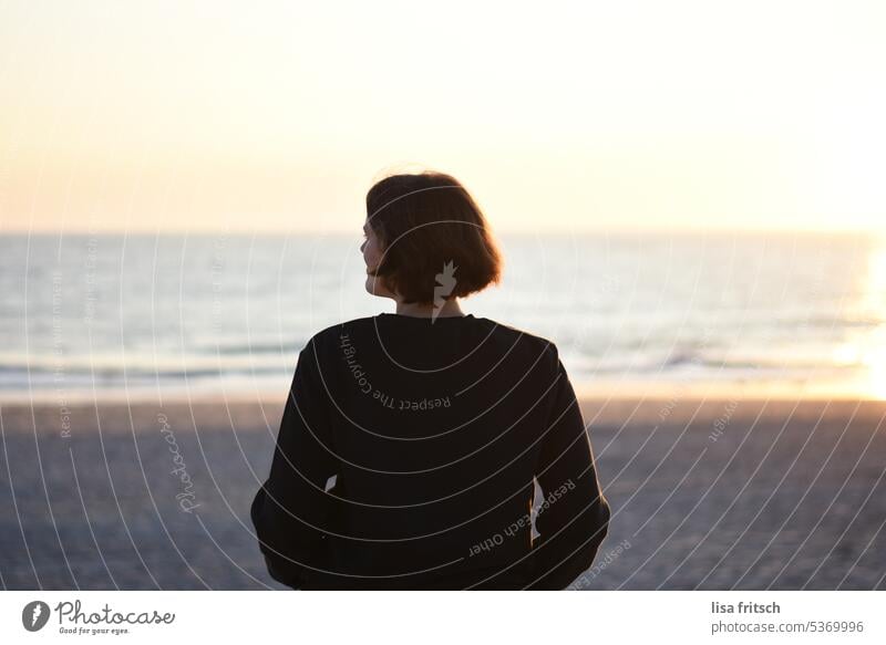 AUSSICHT GENIESSEN - ABENDDÄMMERUNG Frau 30-35 Jahre Rückenansicht Strand Meer Menschenleer kurzhaarig Sonnenlicht Sonnenuntergang Sommer Sommerurlaub