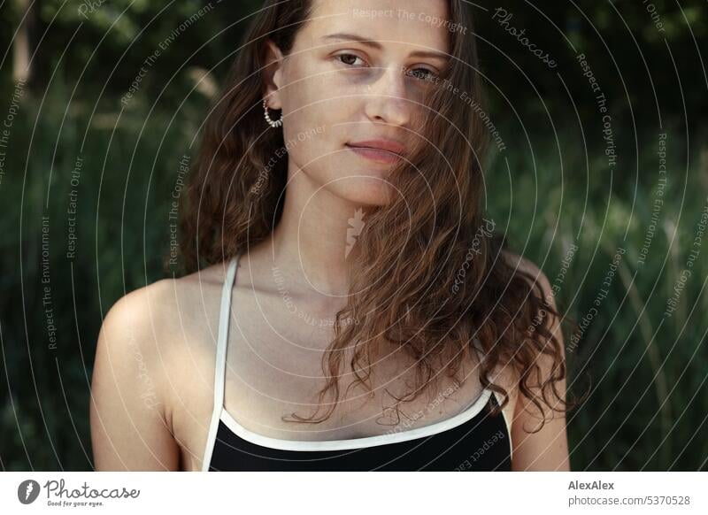 direktes Portrait einer jungen, schönen, brünetten, Frau, die im Sand vor einem Wald sitzt warm sommerlich schönes wetter Sommer Pflanzen Nähe Tag Ruhe