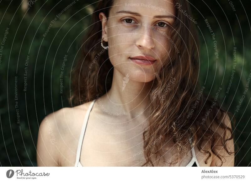 direktes Portrait einer jungen, schönen, brünetten, Frau, die im Sand vor einem Wald sitzt warm sommerlich schönes wetter Sommer Pflanzen Nähe Tag Ruhe