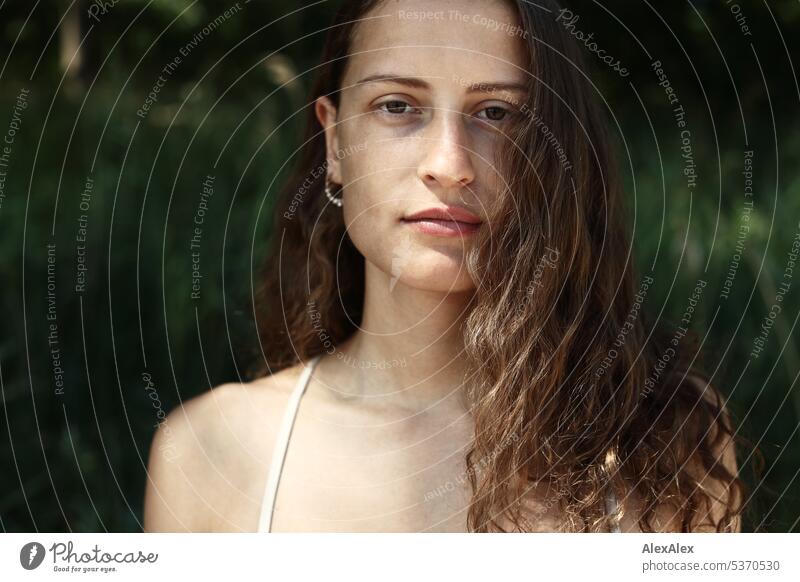 direktes Portrait einer jungen, schönen, brünetten, Frau, die im Sand vor einem Wald sitzt warm sommerlich schönes wetter Sommer Pflanzen Nähe Tag Ruhe