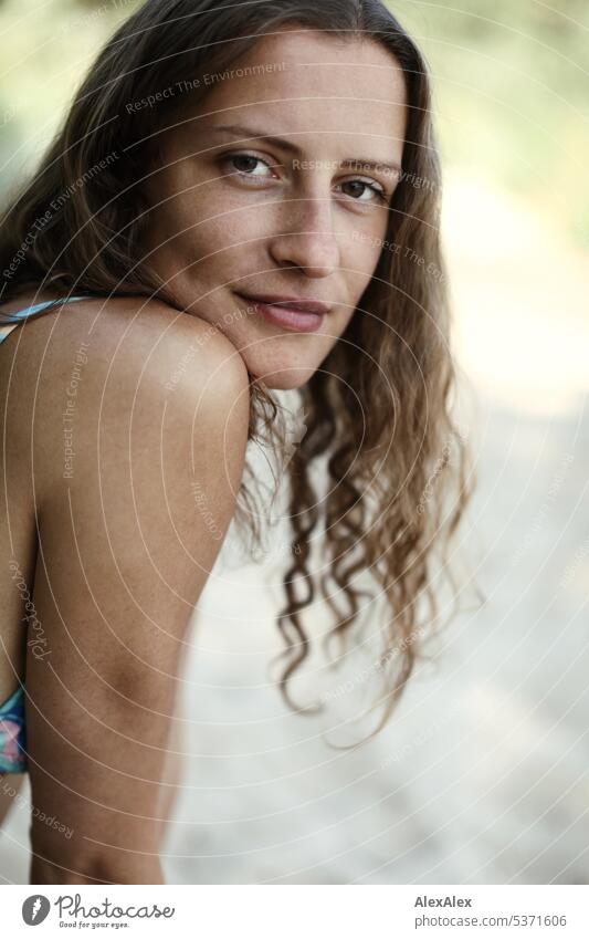 seitliches Portrait einer jungen, schönen, brünetten, lächelnden Frau mit Grübchen im Bikini am Strand warm sommerlich schönes wetter Sommer Nähe Tag