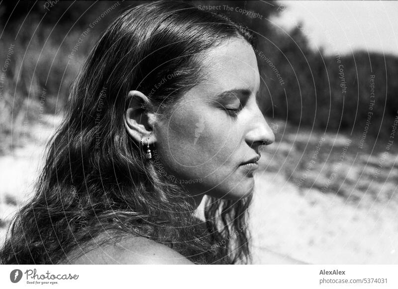 analoges, schwarzweißes, seitliches Portrait einer jungen, schönen, brünetten Frau mit Grübchen am Strand warm sommerlich schönes wetter Sommer Nähe Tag