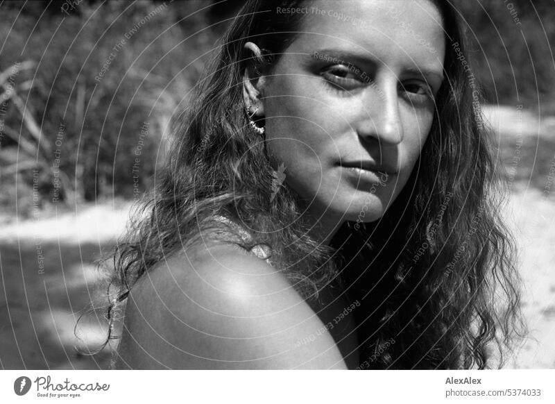 analoges, schwarzweißes, seitliches Portrait einer jungen, schönen, brünetten Frau mit Grübchen am Strand warm sommerlich schönes wetter Sommer Nähe Tag