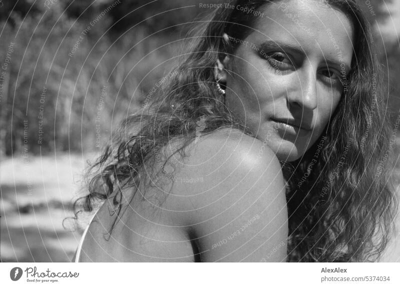 analoges, schwarzweißes, seitliches Portrait einer jungen, schönen, brünetten Frau mit Grübchen am Strand warm sommerlich schönes wetter Sommer Nähe Tag