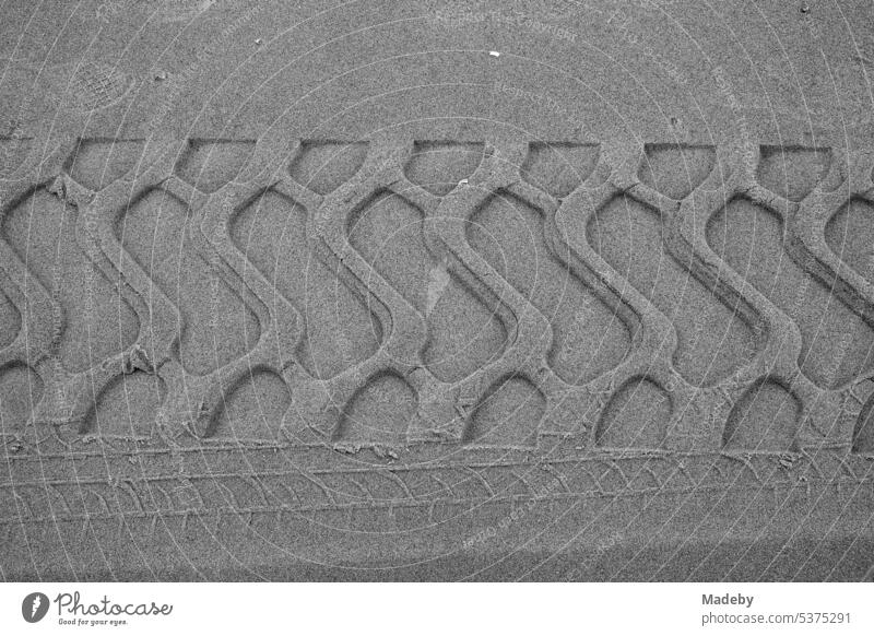 Grobe Reifenspuren im Sand am Strand in Knokke-Heist an der Nordsee bei Brügge in Westflandern in Belgien, fotografiert in klassischem Schwarzweiß Biotop