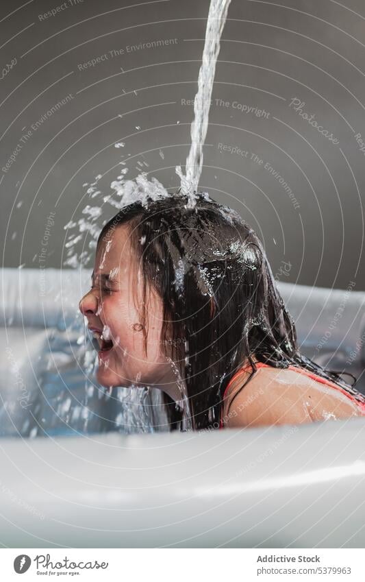 Aufgeregtes Kind, das mit geschlossenen Augen im Kinderbecken schreit schreien Wasser Mund geöffnet Spaß haben Augen geschlossen Glück spielen nasses Haar