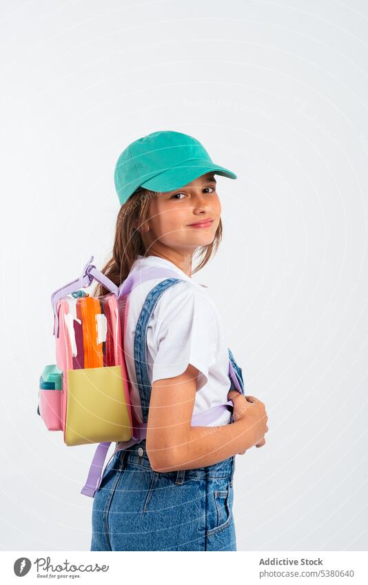 Lächelndes Schulmädchen mit Rucksack und Mütze Mädchen Windstille Kind wenig Stil Hut Kindheit Glück positiv Bildung Schule Studioaufnahme Vorschule elementar