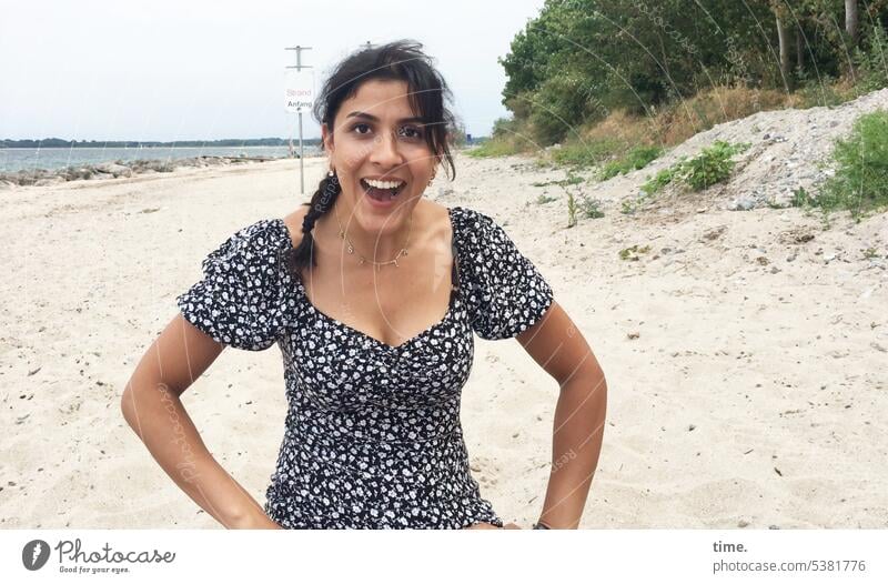 Frau am Strand, angenehm überrascht Kleid Lachen weiblich Portrait Wald Küste Meer Horizont Sand erstaunt dunkelhaarig langhaarig Zopf