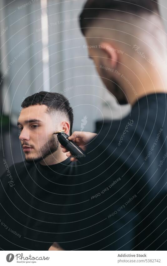 Junger Friseur schneidet Bart im Friseursalon Barbershop Vollbart bärtig Bartiger Mann Schönheit Klinge Pflege Klient Ausschnitt Frisur Kutter Schneiden Typ