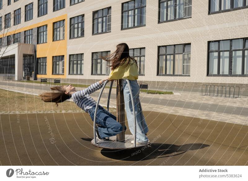 Fröhliche Teenagerfreunde fahren auf einem Kreisverkehr in der Stadt Mädchen Freund Karussell genießen spielerisch Freizeit Zusammensein sorgenfrei Spielplatz