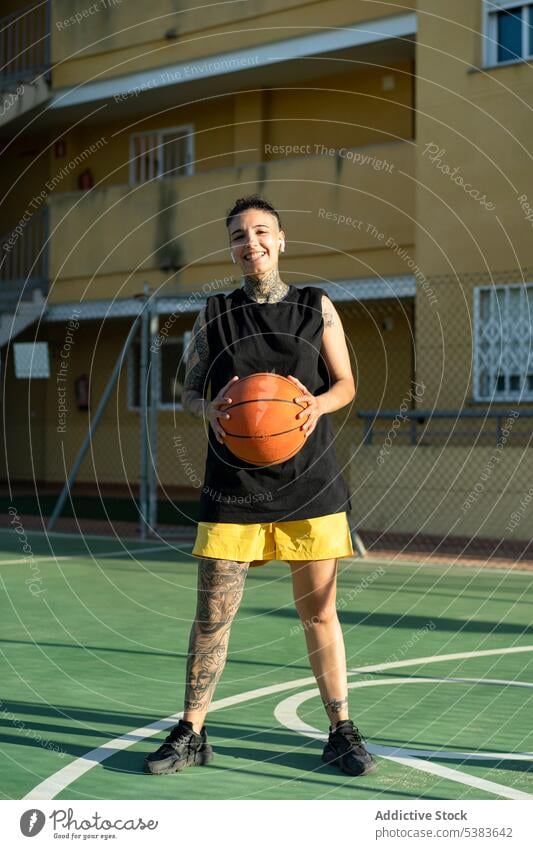 Fröhliche Basketballspielerin mit Ball auf Sportplatz Sportlerin Spieler Sportpark spielen Streetball Spielplatz androgyn brutal maskulin Frau Gericht Training