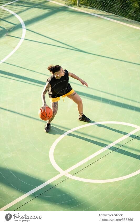 Brutale Frau dribbelt Basketball auf dem Platz Sportlerin Spieler dribbeln Sportpark Ball spielen Streetball Gericht androgyn brutal maskulin Spielplatz