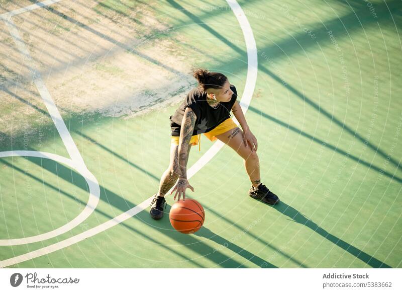 Brutale Frau dribbelt Basketball auf dem Platz Sportlerin Spieler dribbeln Sportpark Ball spielen Streetball Gericht androgyn brutal maskulin Spielplatz