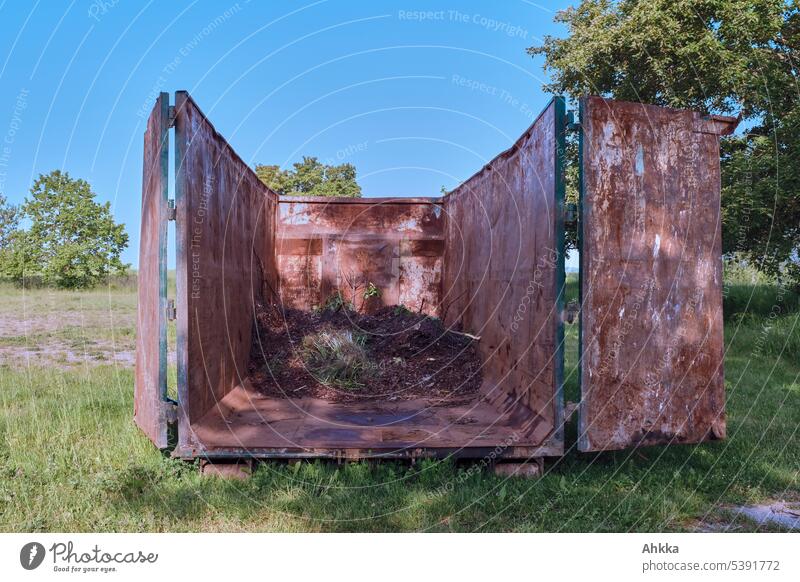 Container mit grünem Abfall zwischen Bäumen auf einer Wiese unter blauem Himmel Müll ökologisch Verwertung nachhaltig Recycling Umweltschutz entsorgen