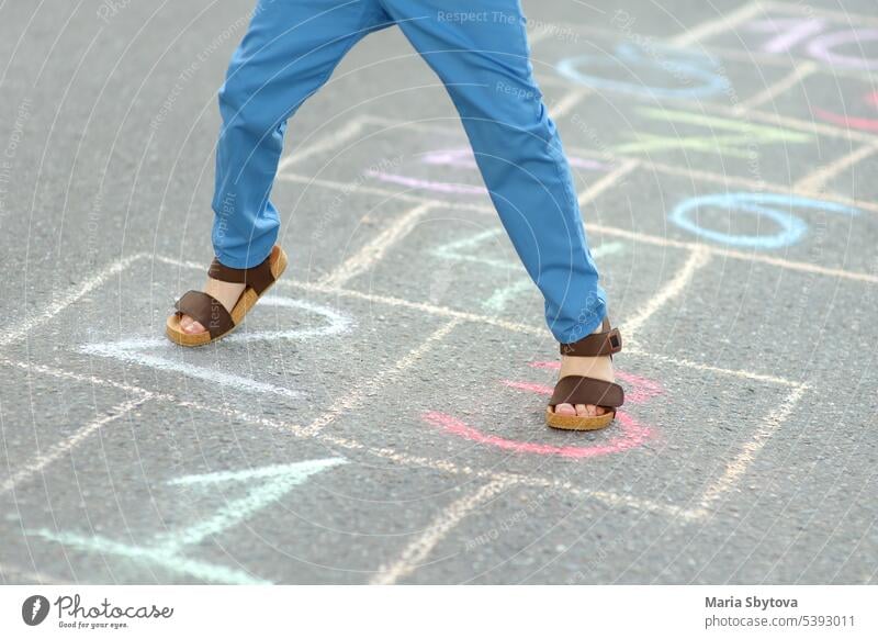 Kleiner Junge die Beine und hopscotch auf Asphalt gezeichnet. Kind spielt hopscotch Spiel auf dem Spielplatz am Frühlingstag. Himmel-und-Hölle-Spiel