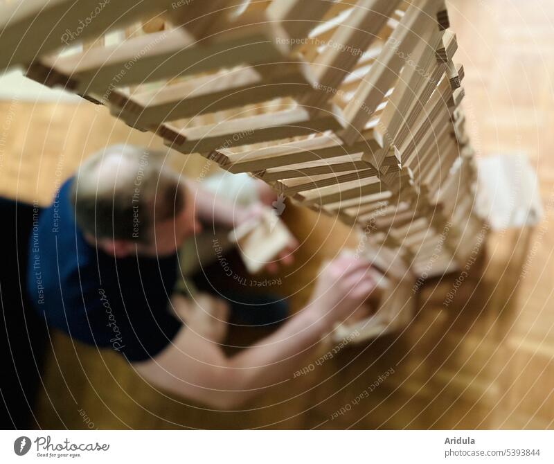 Mann baut Turm aus Holzklötzchen bauen Spielzeug Konstruktion Baustein Blöcke Holzspielzeug Holzbausteine hoch lernen Kindheit Strukturen & Formen