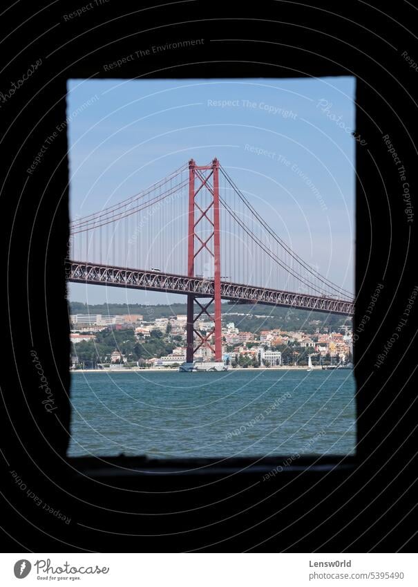 Die berühmte Hängebrücke Ponte 25 de Abril, gesehen durch ein Fenster eines verlassenen Gebäudes in Lissabon, Portugal Architektur blau Brücke Rahmen