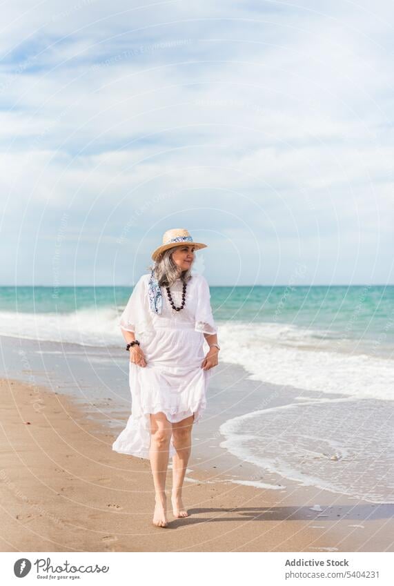 Glückliche Frau, die am Sandstrand spazieren geht Strand Freiheit genießen Urlaub Sommer MEER Natur älter Senior Rentnerin gealtert Ufer winken Wasser