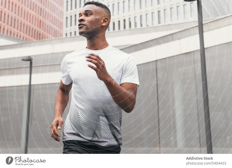 Schwarzer Sportler beim Joggen auf der Stadtstraße Athlet joggen laufen Training Sportbekleidung Turnschuh passen Großstadt Straße männlich schwarz