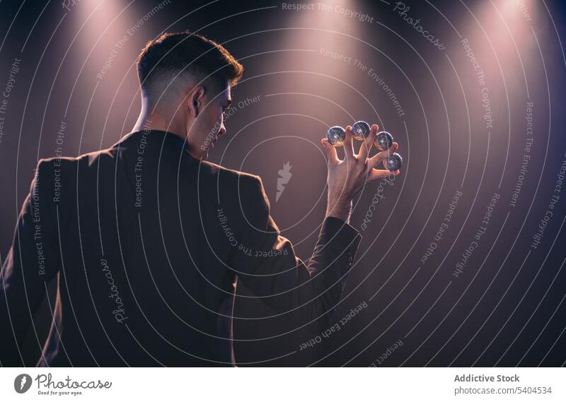 Mann mit Eiern zwischen den Fingern Jongleur Ball ausführen Zirkus schwarz Anzug Schauplatz dunkel männlich zeigen Sinnestäuschung Luftspiegelung