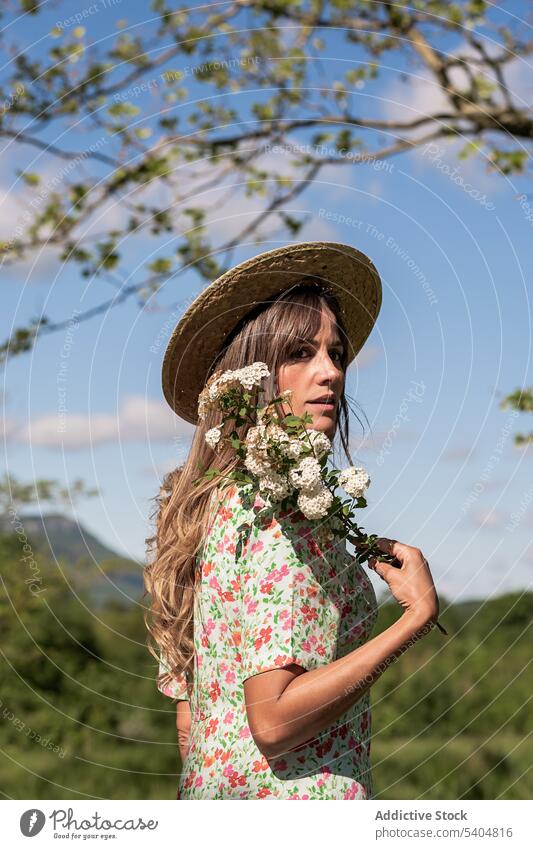 Ruhige Frau mit Blumen in sommerlicher Landschaft träumen Sommer Natur Feld Blüte Blumenstrauß romantisch Kleid Garten ländlich Strohhut Wiese idyllisch