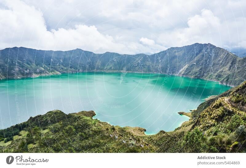 Blauer See umgeben von Bergen mit grünen Bäumen im Sonnenlicht Rippeln Wasser Berge u. Gebirge felsig Landschaft Baum bedeckt malerisch Natur Bucht Hochland