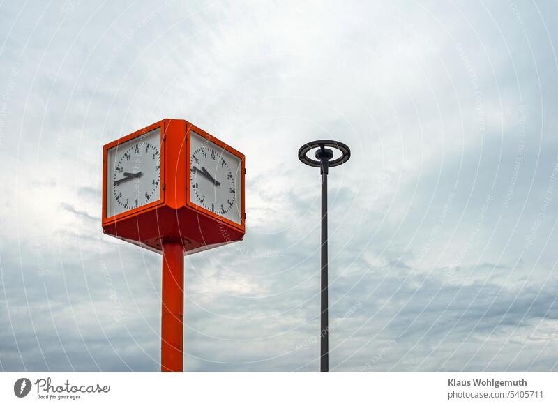 Grauer Himmel über einer öffentlichen Uhr und einer runden Straßenlampe grauer Himmel bewölkter Himmel Hintergrund Standuhr Bahnhofsuhr eckig Würfelform